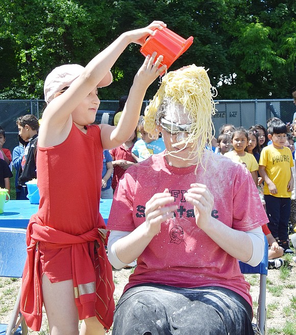 Yeyling Zhungo, second-grader, dumps a pail of pasta onto school nurse Lissa Feigenbaum.