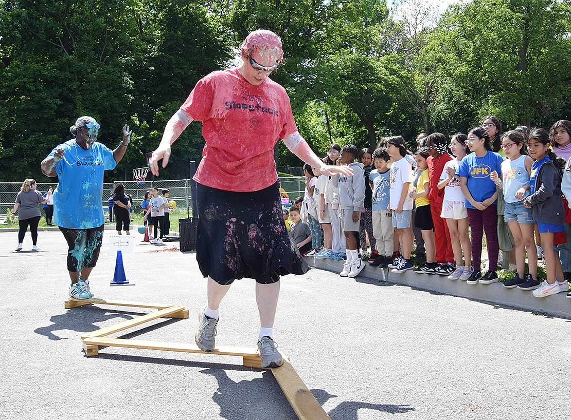 PTA President DiAndra Dempson (back) and nurse Lissa Feigenbaum navigate a balance beam after being covered in flour, pasta and slime.