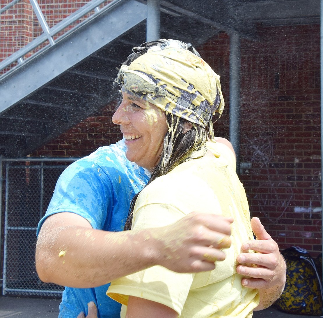 Jeanine Maiolini, a physical education teacher on the Yellow Team, the champions of the day, shares a messy hug with her health colleague Daniel Maldonado.