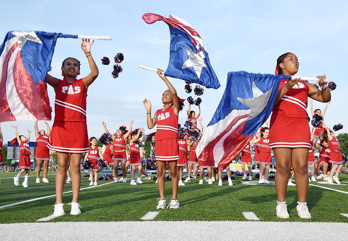 Park Avenue School spirit is abounding at the annual Band Night on Tuesday, June 4. Closing out their routine, fifth-graders Kylie Gourdine (left), Charli Pierce and Olivia Singleton spin flags while their fellow squad members cheer behind them on the Port Chester High School football field.