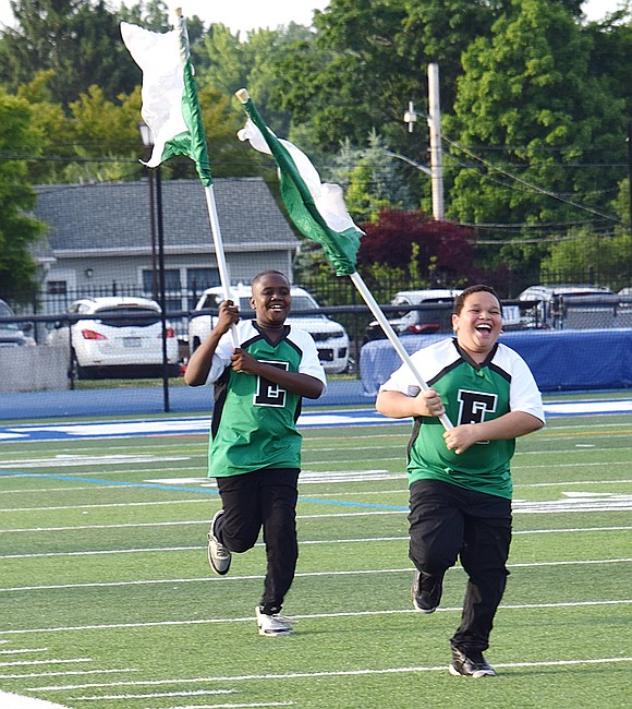 It’s all fun and laughs for Edison School fourth-grader Marvin Findley (left) and fifth-grader Isaiah Estevez, who embrace their role of running across the field with flags.