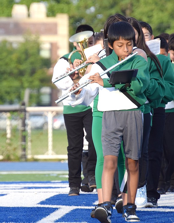 Wearing Edison School’s green and white colors, fifth-grade flutist Ruben Mosso-Tapia plays the school’s song while marching into position.