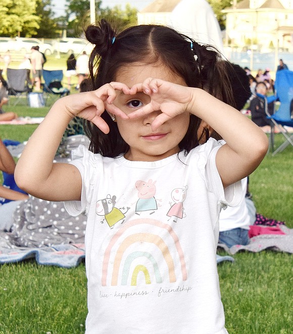 Quintard Drive resident Gabriella Guayllasaca, 3, makes a heart with her hands ahead of the “Jumanji” showing during the Port Chester High School club Ram Nation’s community movie night on June 7.