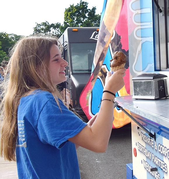 Kate Richardson, a junior at Port Chester High School, snags a chocolate ice cream cone from one of the food trucks lined up along Park Avenue.