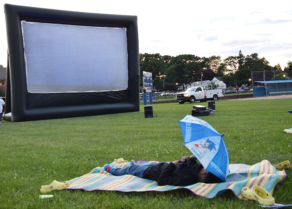 Having secured a spot close to the inflatable screen, King Street School third-grader Axel Saquicela casually waits for the showing of the 2017 adventure flick “Jumanji” on June 7. The second annual movie night at Port Chester High School saw 500 people attending, according to Ram Nation, the organizing club dedicated to strengthening school and community culture.