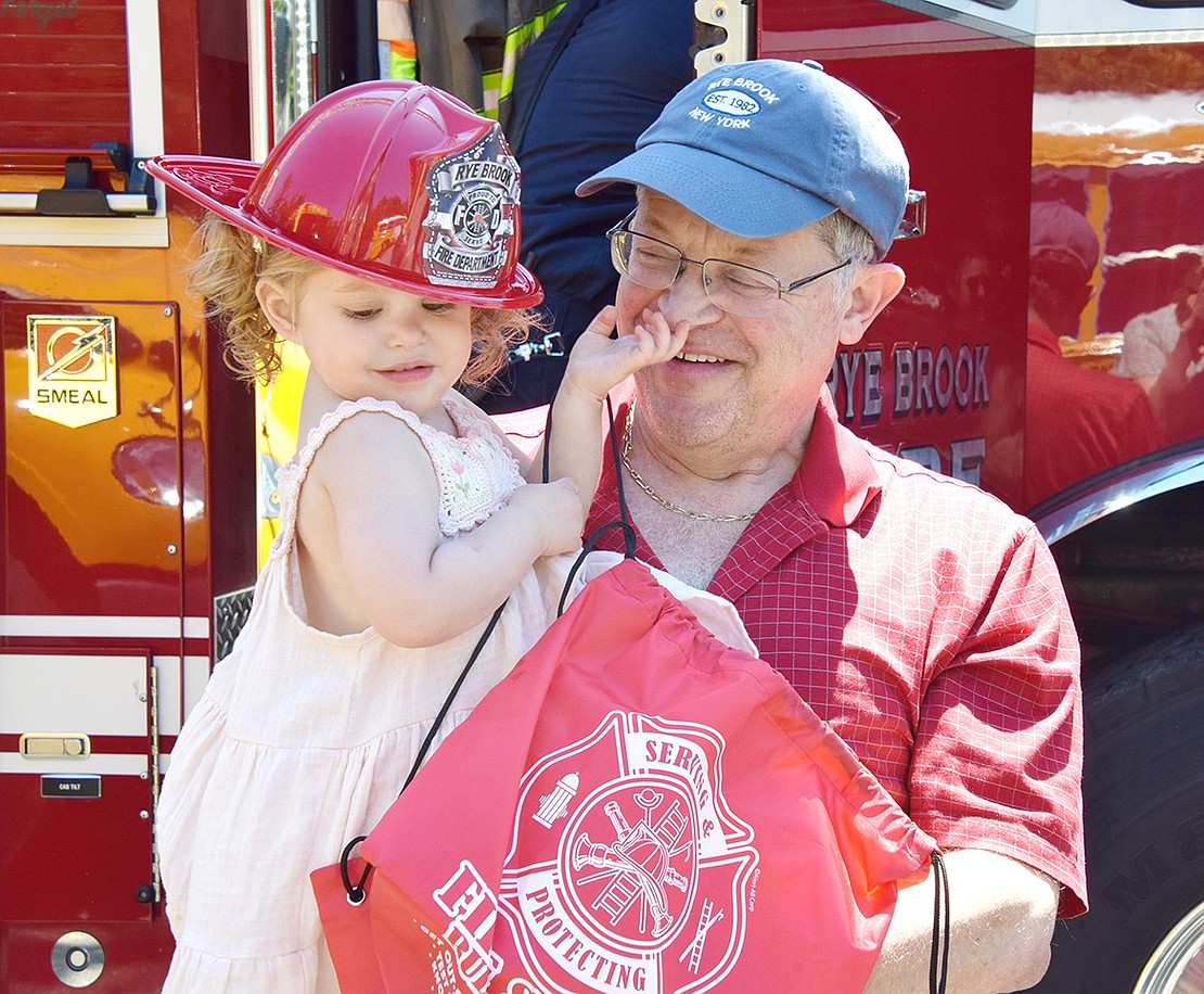 A proud Rye Brook grandfather, Giorgio Rietti, smiles as he gets a nose honk from his visiting granddaughter Lillian, 2, who is happy to don her new village fire department hat.