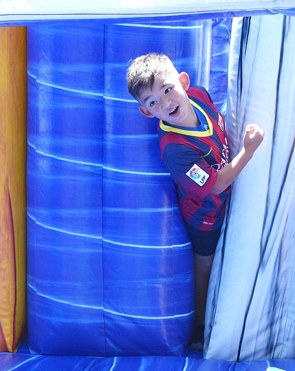 Jordan Rivera, a 7-year-old John F. Kennedy Elementary School student, squeezes out of an inflatable obstacle course after bolting through the intricate structure.