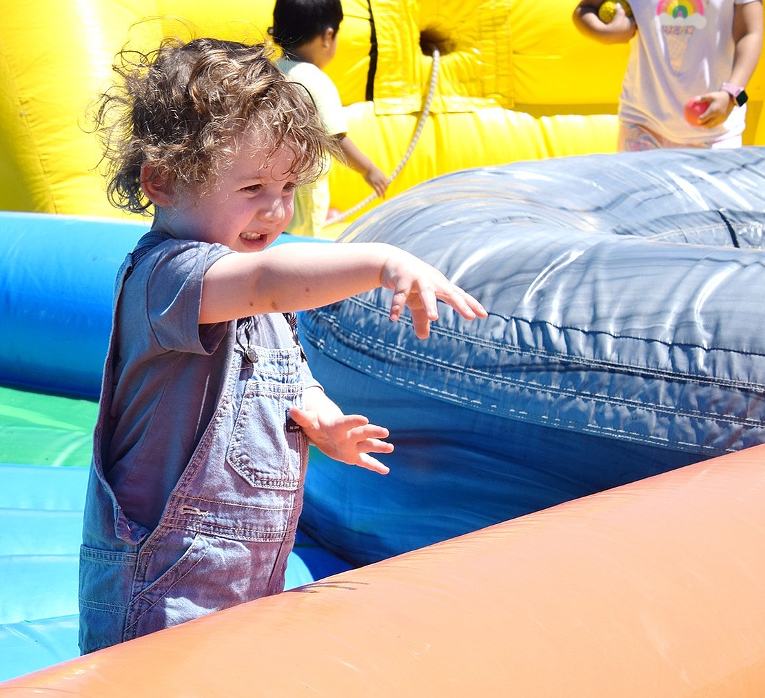 Giving it all he’s got, 1-year-old Aiden Waine of Rye Brook tosses a ball toward other children playing on a bouncy attraction.