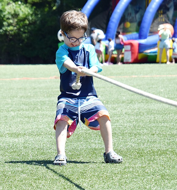 Seth Frenklakh, a 5-year-old Betsy Brown Road resident, tries with all his might to win a tug-o-war challenge against two other children half his age.