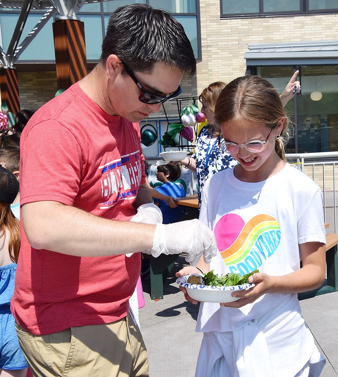 Blind Brook PTA parent Cameron Sager serves third-grader Poppy Schueller a pinch of scallions she had a hand in planting in the school’s new greenhouse and courtyard gardens. She, and every other student at Ridge Street School, got the chance to enjoy food they grew at the school’s first Saladbration on Tuesday, June 18.