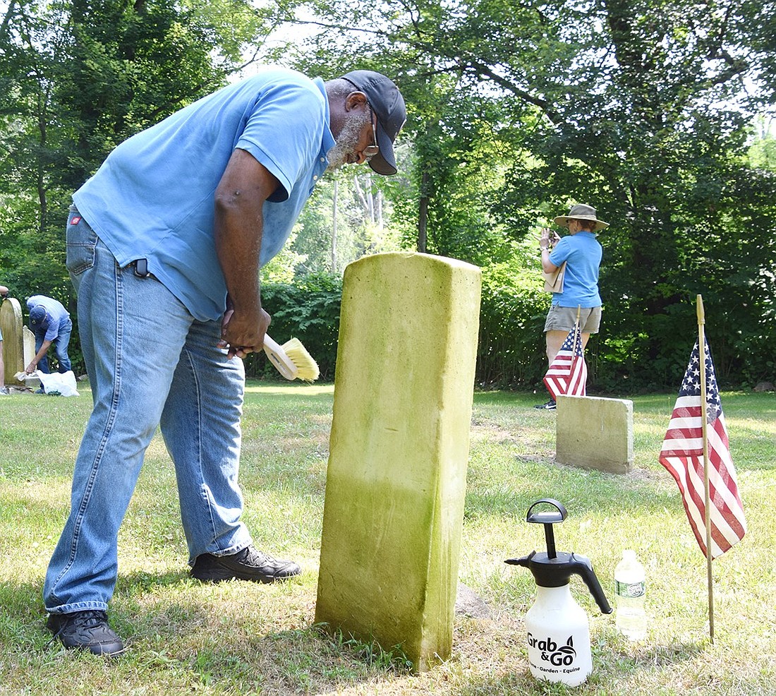 Friends of the African American Cemetery Founder Dave Thomas of Port Chester scrubs down a headstone marking a veteran buried in the hallowed grounds as part of a service project to celebrate Juneteenth on Saturday, June 22.