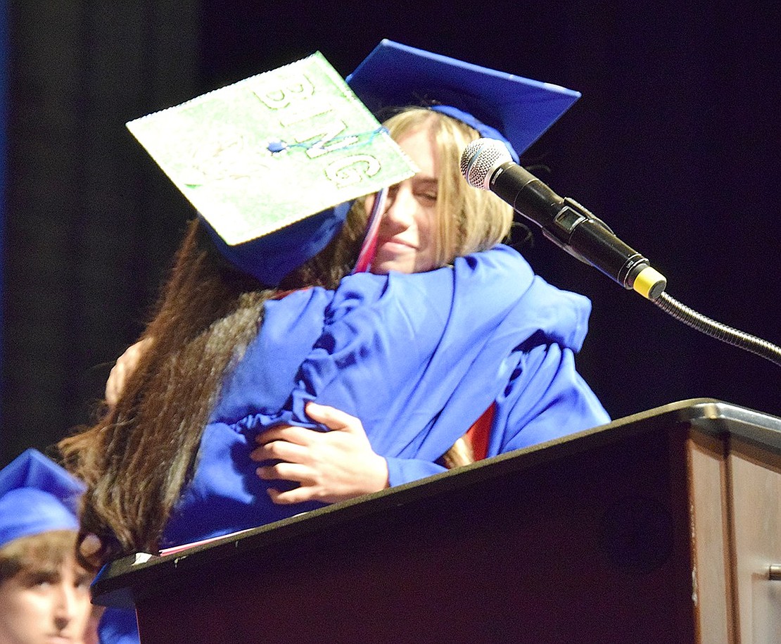 Welcoming her dear friend to the podium, Ella Piacente (left) hugs Ana Savitt before she delivers a speech as one of the two class speakers.