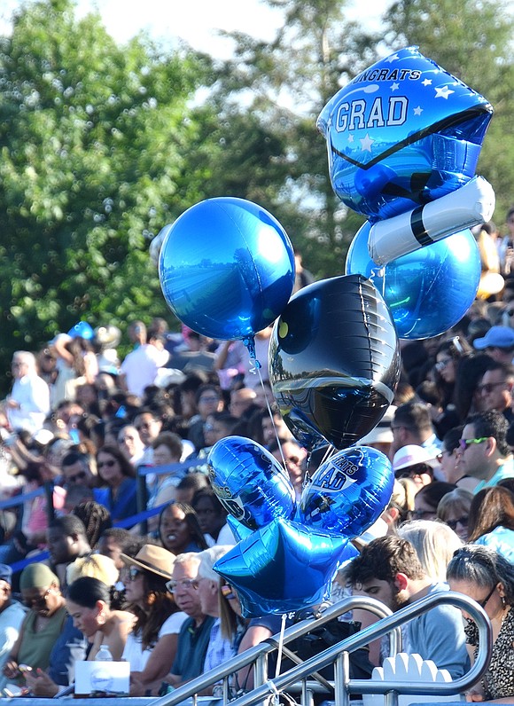 Balloons waiting to be handed off to a happy graduate hover in the stadium.