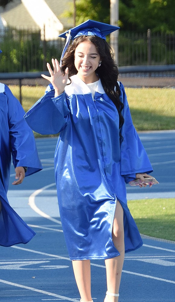 Elisavet Ascencio puts on a giddy face as she marches into the stadium to the tune of “Pomp and Circumstance.”