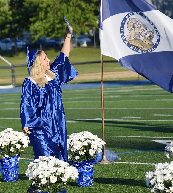 Sabrina Contreras shows off her fresh diploma as she walks by the Port Chester High School flag.