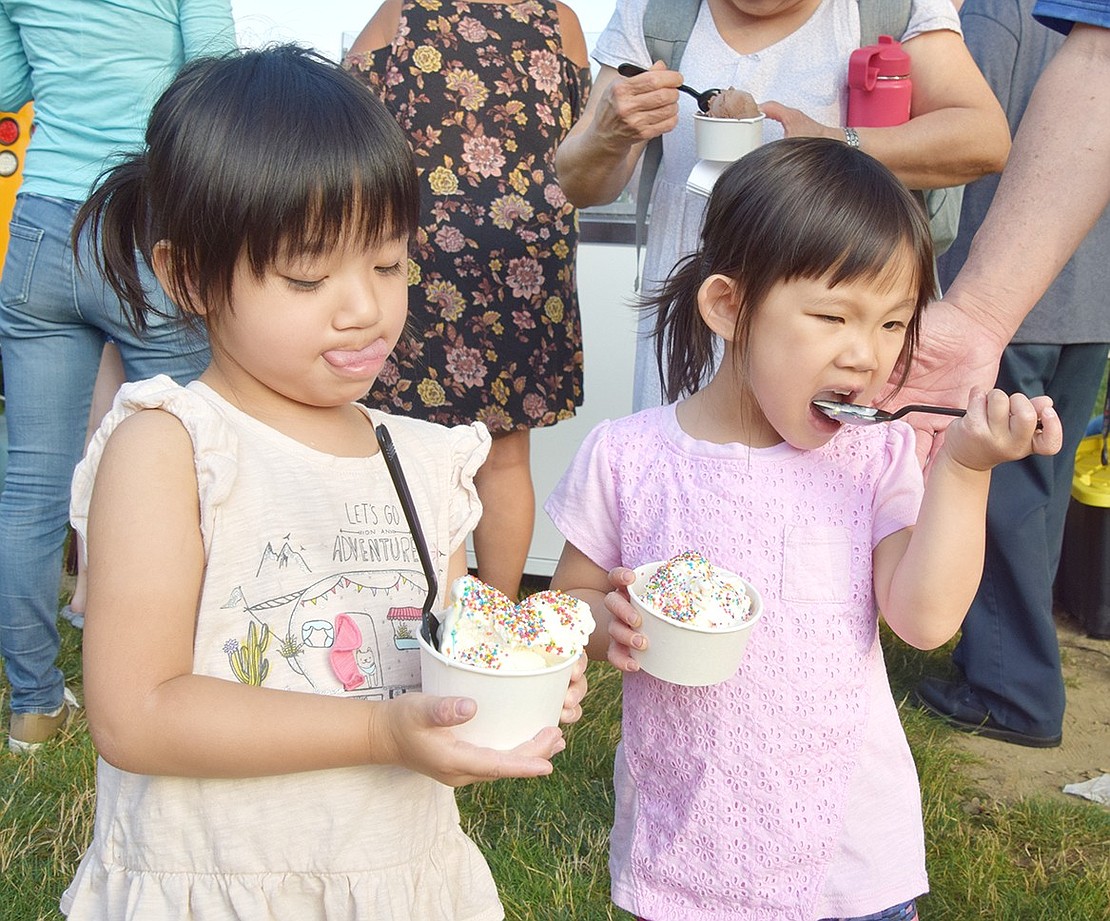 While 3-year-old Valley Terrace resident Evie Lim (left) eyes her sweet snack, her twin sister Julie wastes little time digging in.