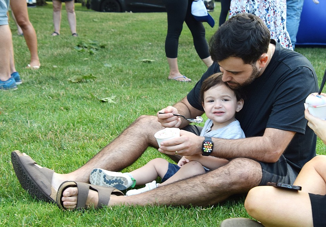 Looking to make the best of Ice Cream Friday, Concord Place resident Zev Moshon tries to feed his son Ethan a spoonful of his vanilla scoop on July 5, but the 2-year-old is more interested in the camera. The Village of Rye Brook invites the public to Pine Ridge Park every Friday in July for free ice cream, music and a bounce house.