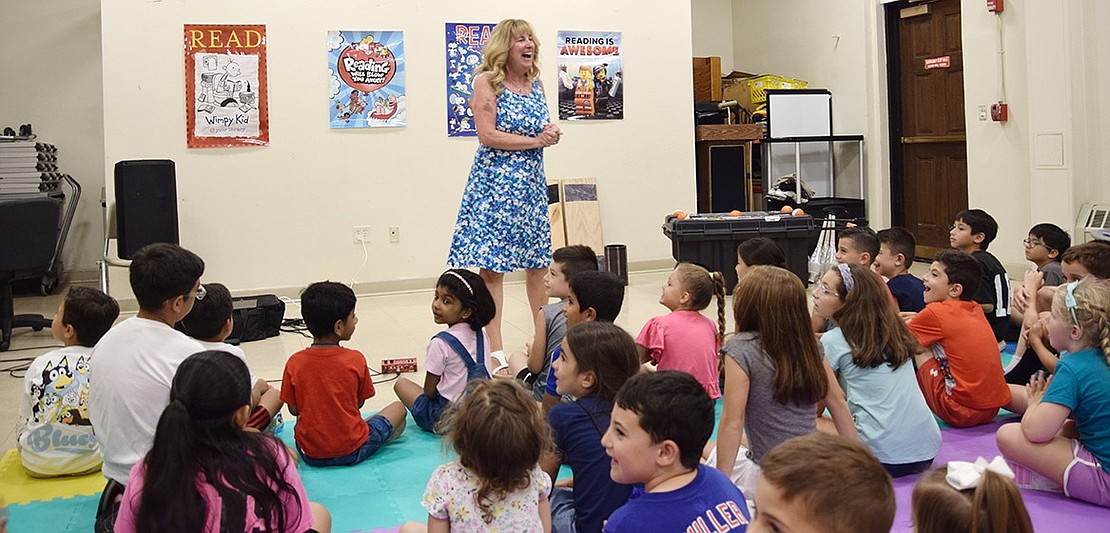 Children’s Librarian Tee Cotter warms up the crowd of 35 kids and prepares to introduce Long Island-based entertainer Jester Jim.