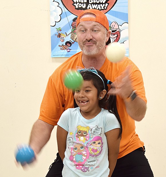 Six-year-old Alyssa Melchor of Grace Church Street can’t hold in her laughter as Jester Jim juggles around her during a children’s show at the Port Chester-Rye Brook Public Library on July 8. Young attendees laughed as he cracked jokes, beatboxed and performed circus acts at the event sponsored by the Friends of the Port Chester-Rye Brook Public Library.