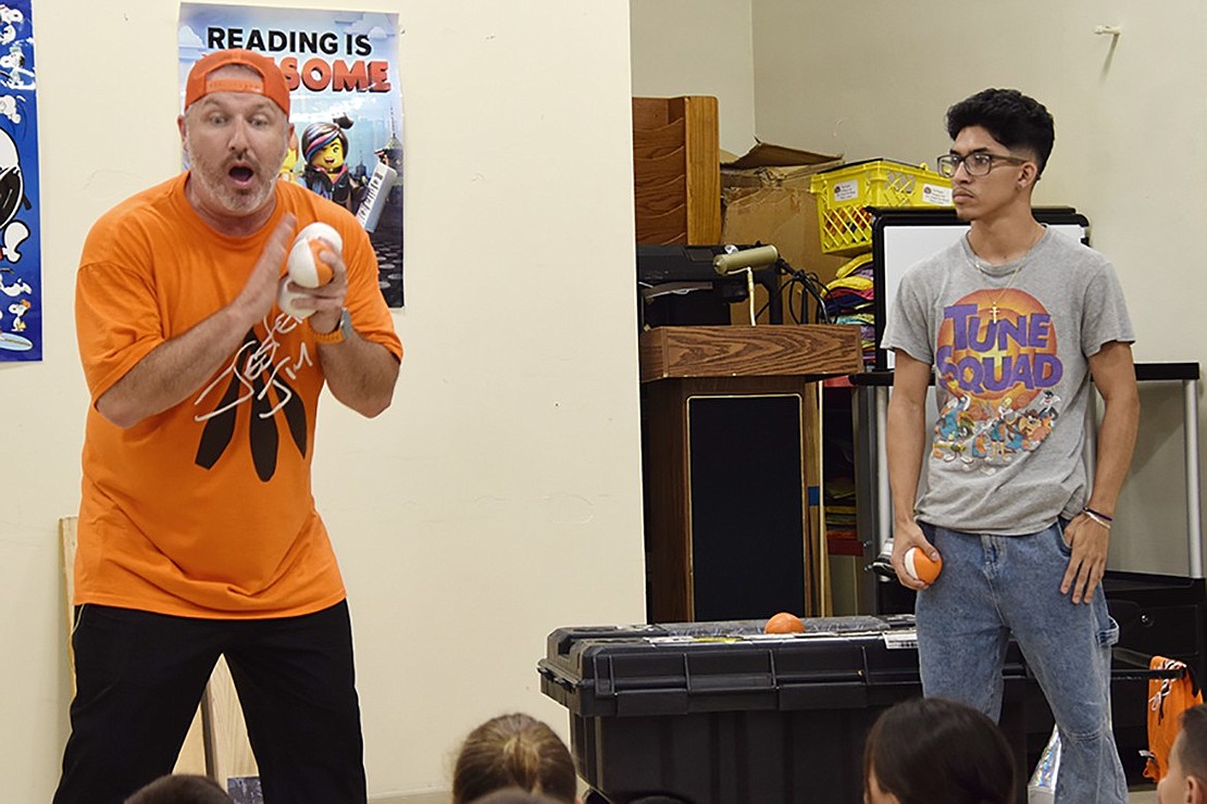 Jester Jim asks Library Assistant Nicholas Bolanos, who graduated from Port Chester High School in 2022, to help in his juggling act.