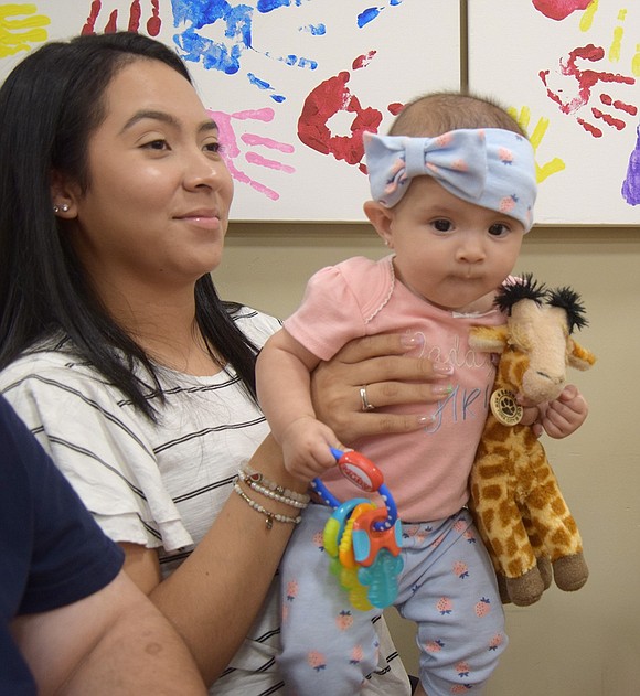 Greenwood Avenue resident Michelle Gudino does her best to keep her 6-month-old daughter Madelyn focused on the show.