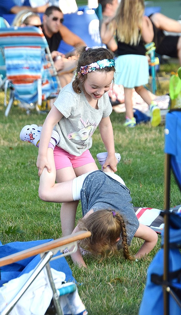 Goofing around after a spurt of dancing, 4-year-old Rye Brook resident Mia Taub tries to lift her twin sister Audrey for some wheelbarrow walking in their neighborhood park.