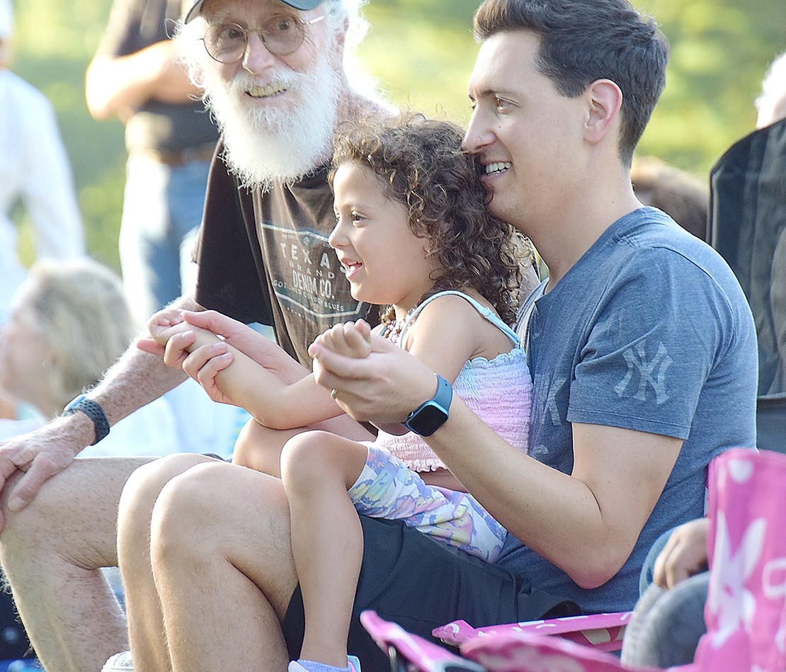 Four-year-old Evie Hoch curls up on the lap of her father Ethan for a bonding moment. He holds her hands so they can clap to the beat together.