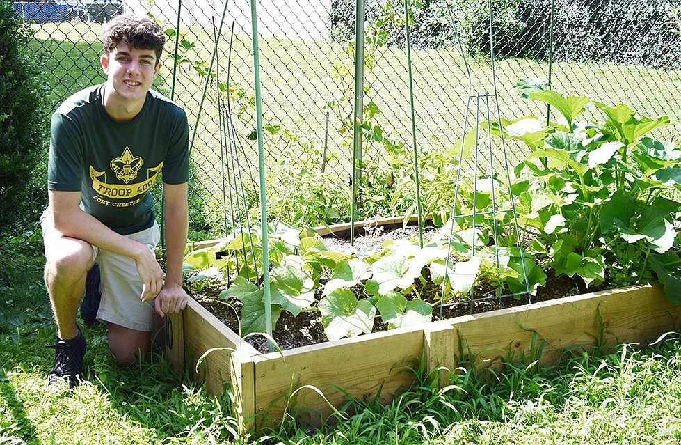 Trevor Sullivan, one of the newest BSA Troop 400 Eagle Scouts, poses with a garden bed at the Weber Drive Community Garden on Friday, July 19. He, along with Dominic Portillo, received the prestigious rank for their work in the green space.