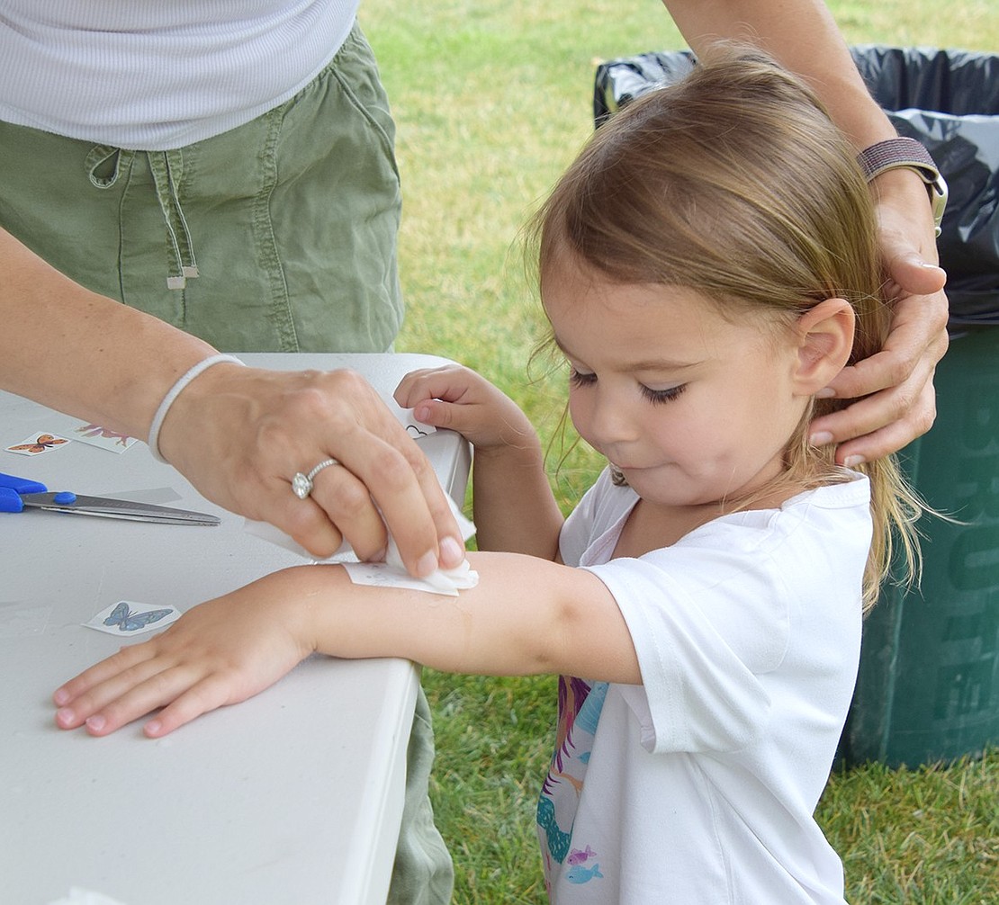 Harper Harris, a 3-year-old Windingwood Road resident, patiently waits for a temporary tattoo to dry after application.