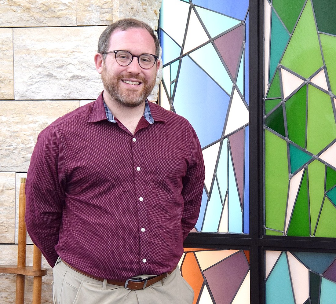 After speaking about his new commitment that will keep him in the community for the next five years, Congregation KTI Rabbi Ben Goldberg poses for a photo in front of the synagogue’s colorful ark doors representing the 12 tribes of Israel on July 24.