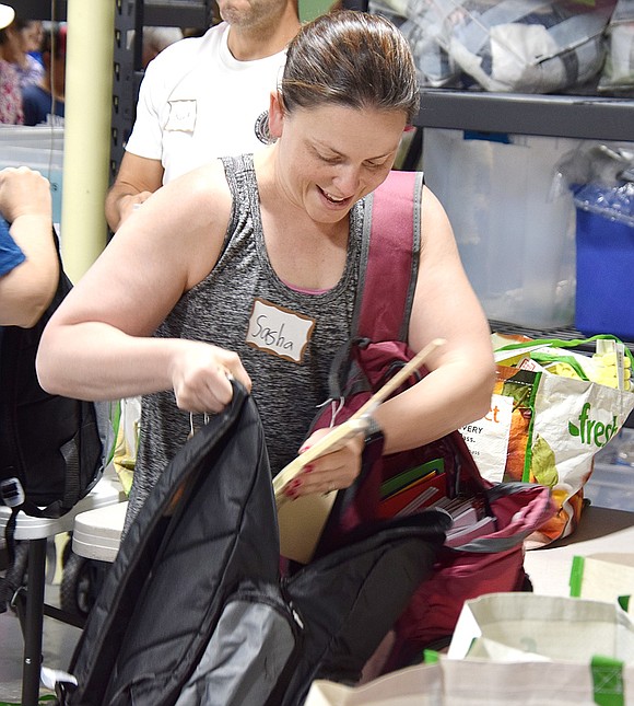 Demonstrating efficiency, Larchmont resident Sasha Shapiro carries two backpacks through the assembly line that will eventually be in the hands of high schoolers in the county.