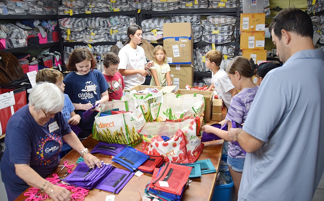 In the rear of the Purdy Avenue warehouse, a group of children circle around their own packing table to stuff pouches with various school supplies.