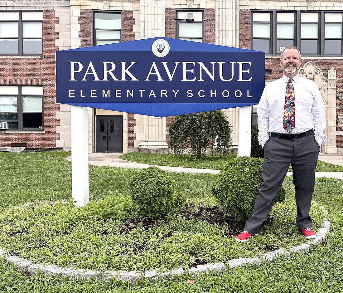 As the new principal of Park Avenue Elementary School, Craig Dreves poses with the sign in front of the building on Aug. 7 after discussing his world travels and ambitions that brought him back to his hometown and alma mater: Port Chester.