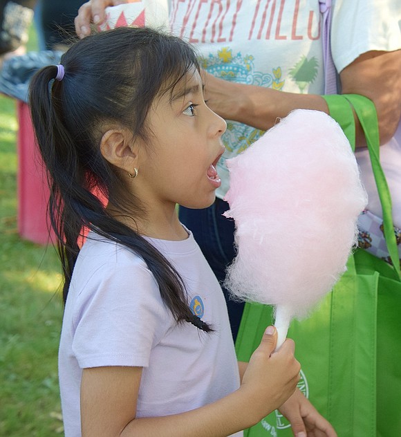 After patiently waiting in line, Grove Street resident Mia Estrada, 5, takes a bite out of some cotton candy.