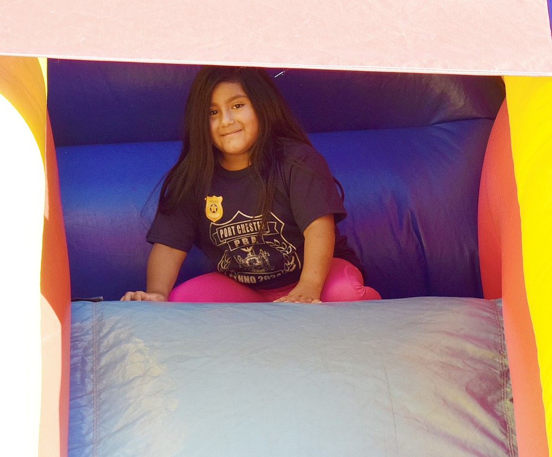 Gina Cando, a 6-year-old resident of Locust Avenue, pauses at the top of an inflatable slide to smile for the camera.