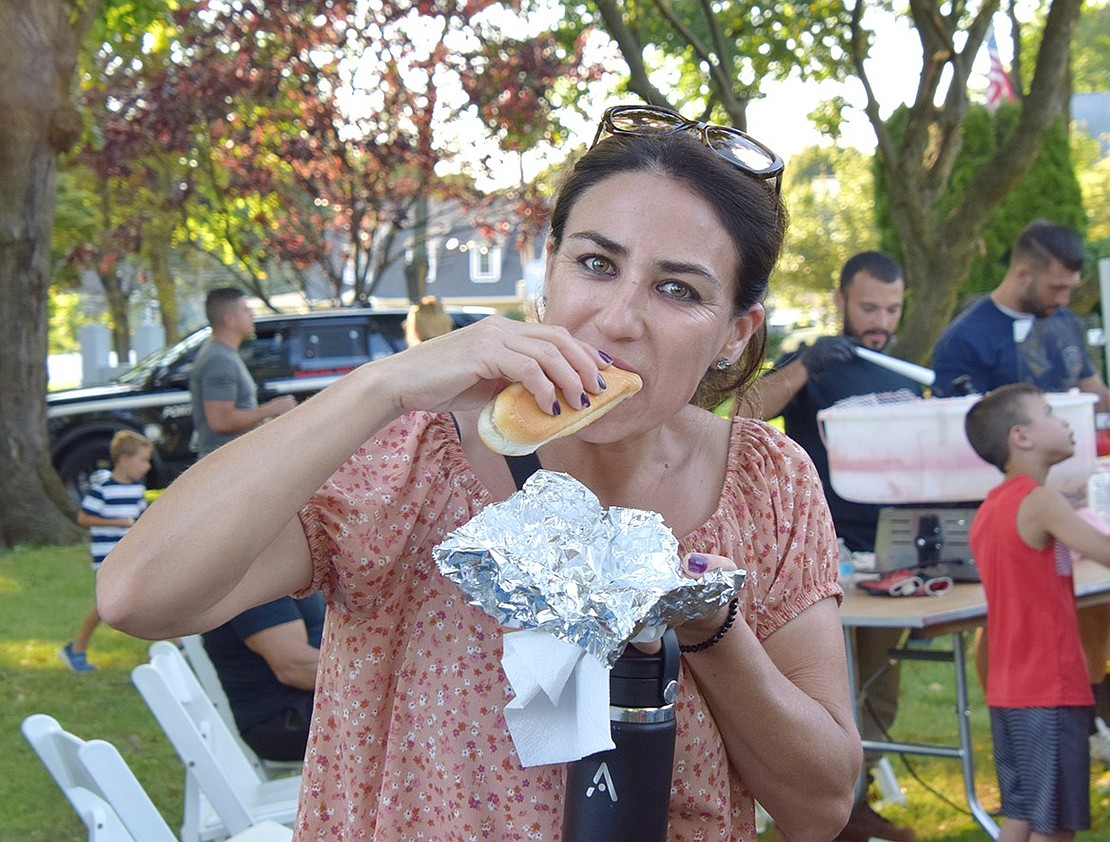 Grove Street resident Ana Gonzales takes a bite out of a hot dog, handed out by officers throughout the evening.