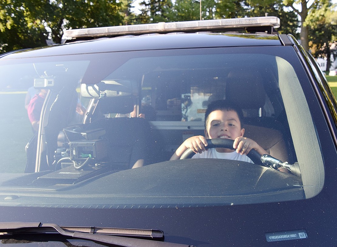 Barely tall enough to see over the steering wheel, 5-year-old Anderson Cardona of Park Avenue takes in the view from the driver’s seat of a police cruiser.