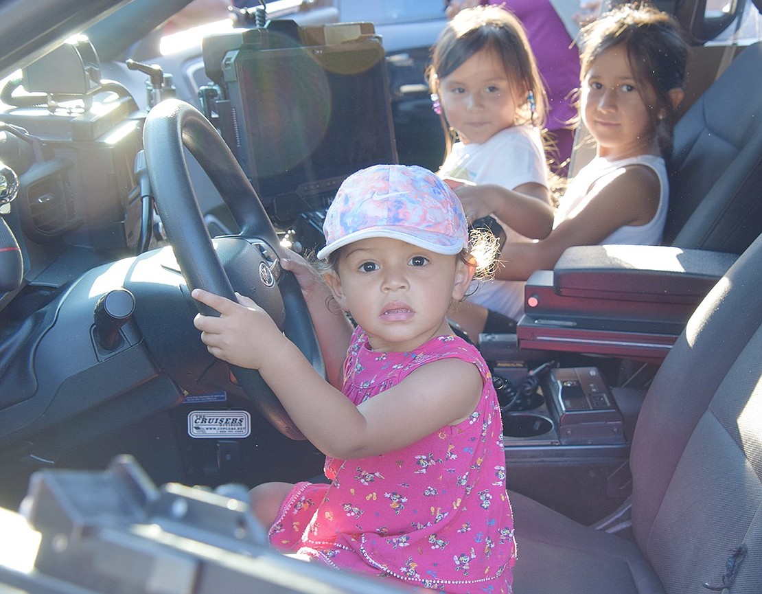 Riley Marin, a 2-year-old Park Avenue resident, finds herself in the driver’s seat of a police cruiser. In the passenger seat, Halstead Avenue residents 4-year-old Leilani Escobar and 7-year-old Diana Samano pose for the camera.