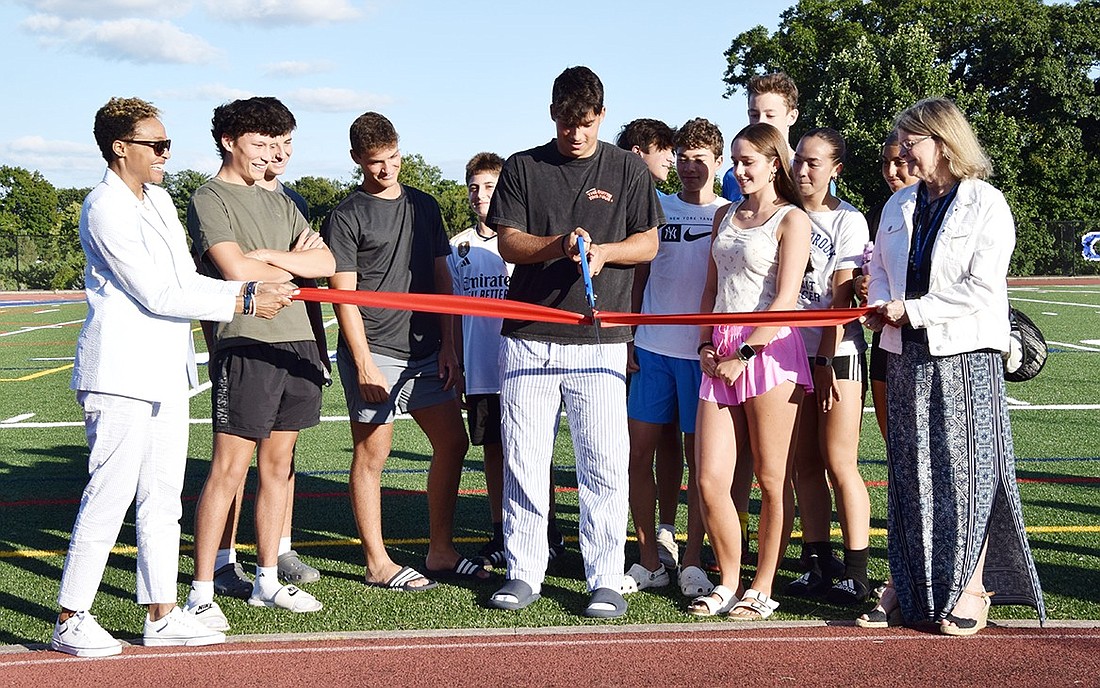 Rising junior Tyler Taerstein (center), surrounded by fellow Blind Brook student athletes, cuts a ribbon to commemorate the completion of the multipurpose field at the high school on Tuesday, Aug. 20. The field, along with the baseball diamond, was shut down in March after failing a safety test.