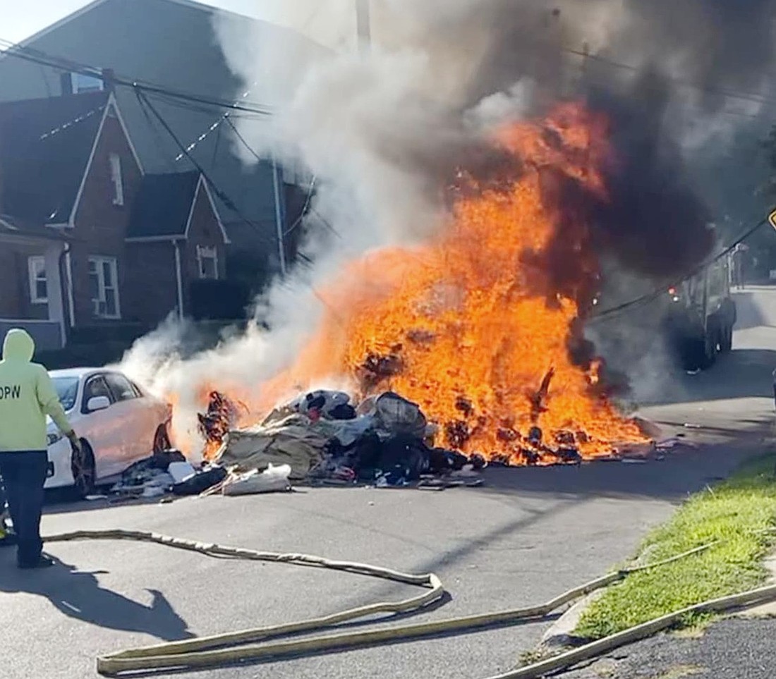 A fire blazes on Gilbert Place after burning garbage removed from a Port Chester sanitation truck was unloaded onto the street on Wednesday, Aug. 21. The flames originated from a damaged lithium-ion battery.