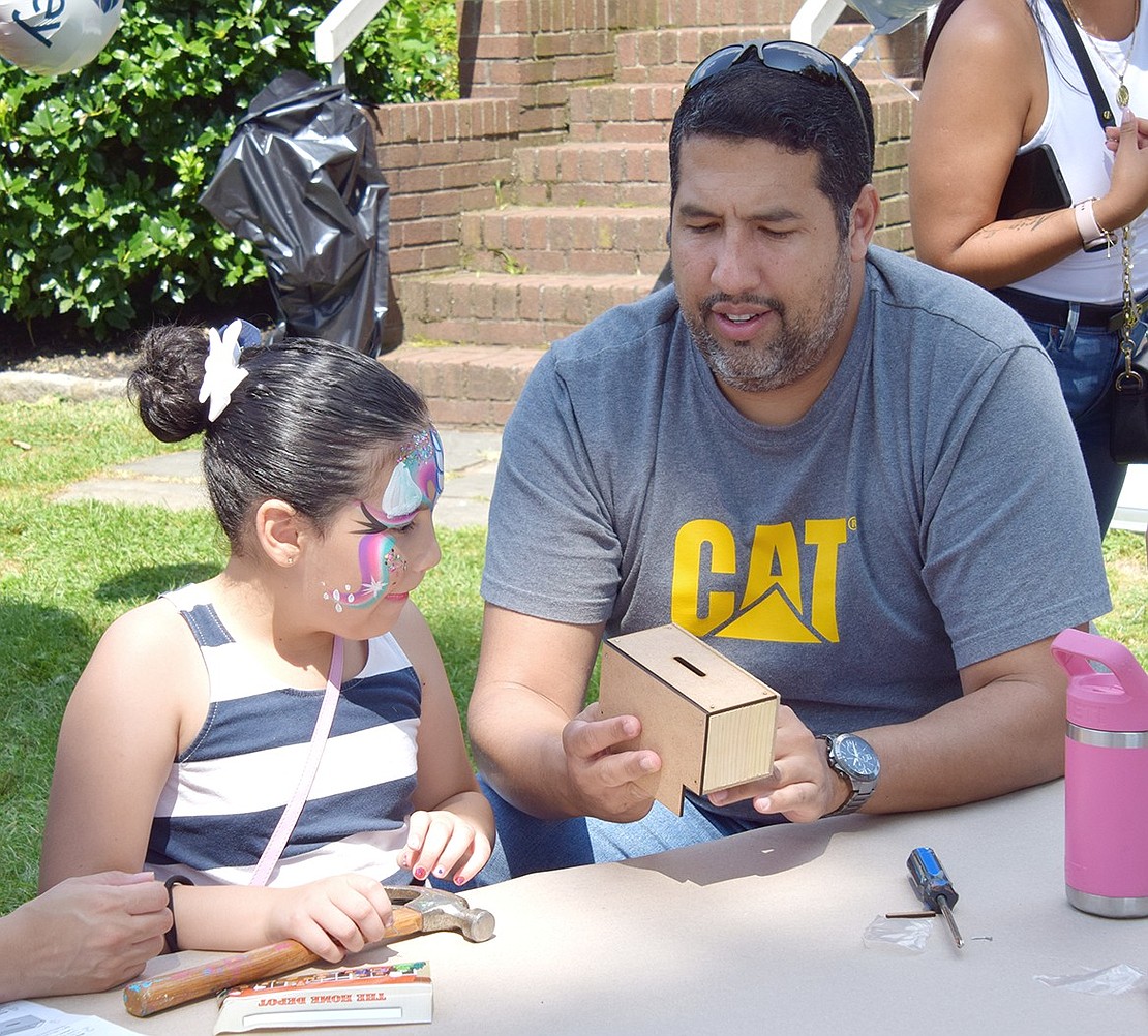 Westview Avenue, Rye Brook, 6-year-old Celeste Morales works with her dad Diego to build a wooden coin bank at The Home Depot table.