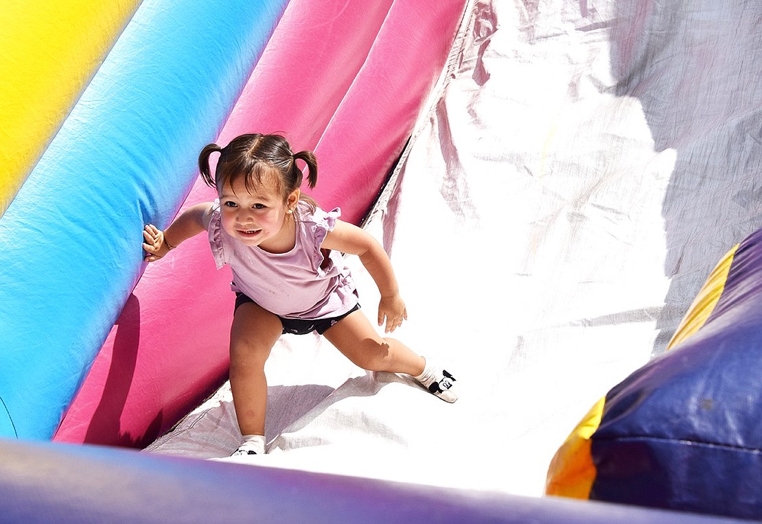 Amelia Garcia, a 2-year-old Riverdale Avenue resident, regains her footing after tumbling down an inflatable slide at Port Chester Day on Saturday, Aug. 24. Hundreds gathered at Lyon Park to celebrate the 35th year of the event.