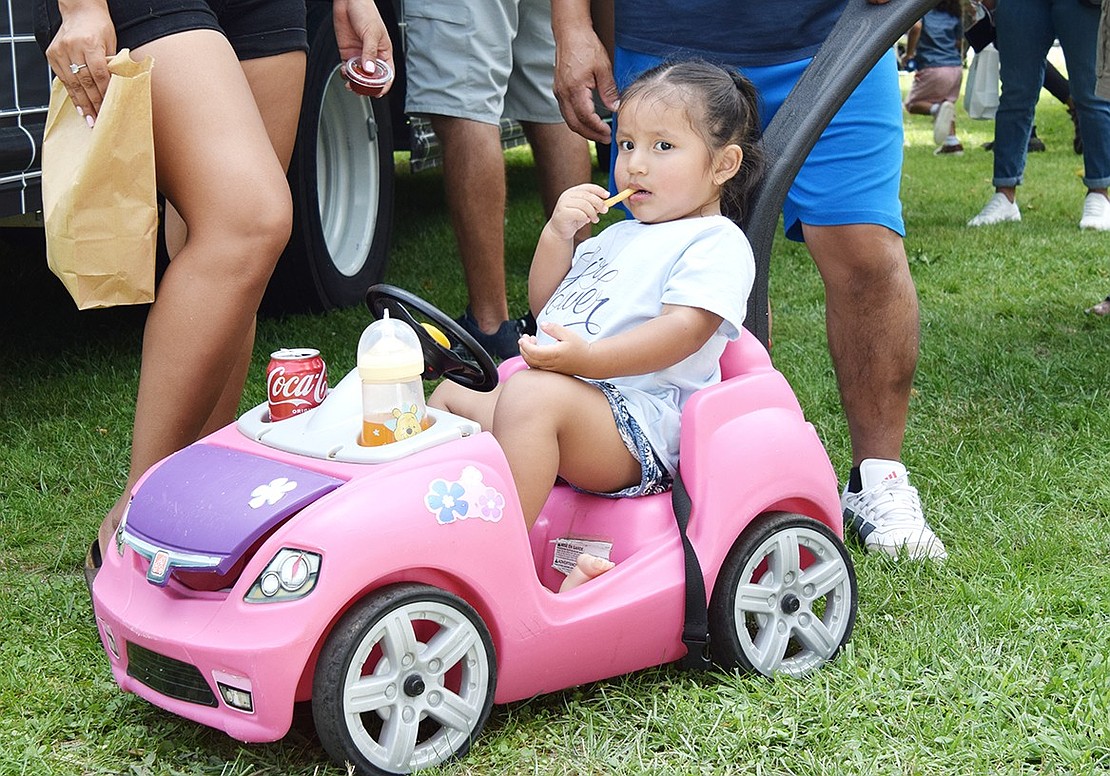 Leicester Street resident Lillian Yupangui, 2, leisurely eats a fry from the comfort of her pink ride.