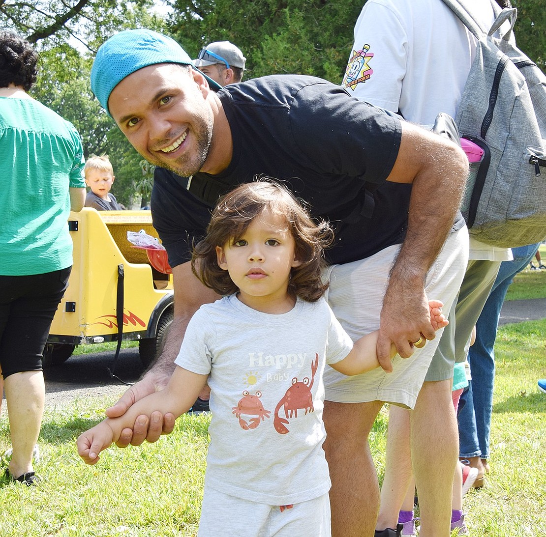 Westchester Avenue resident Miguel Colmenares poses with his 2-year-old son Andrew while they wait in line for the train that circles the park.