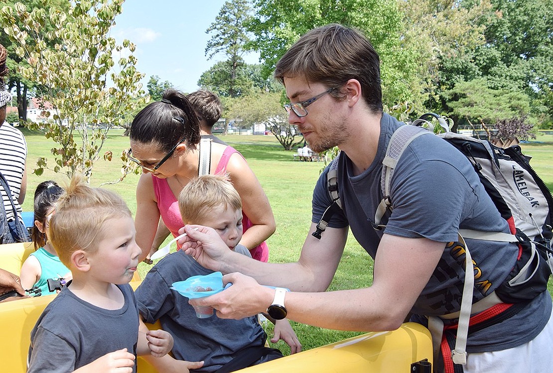 Augie Farellio (left), a 5-year-old Washington Mews resident, gets a last-second bite of an Italian Ice from his father Ben before heading off to ride a train around Lyon Park with his 7-year-old brother Andrew.