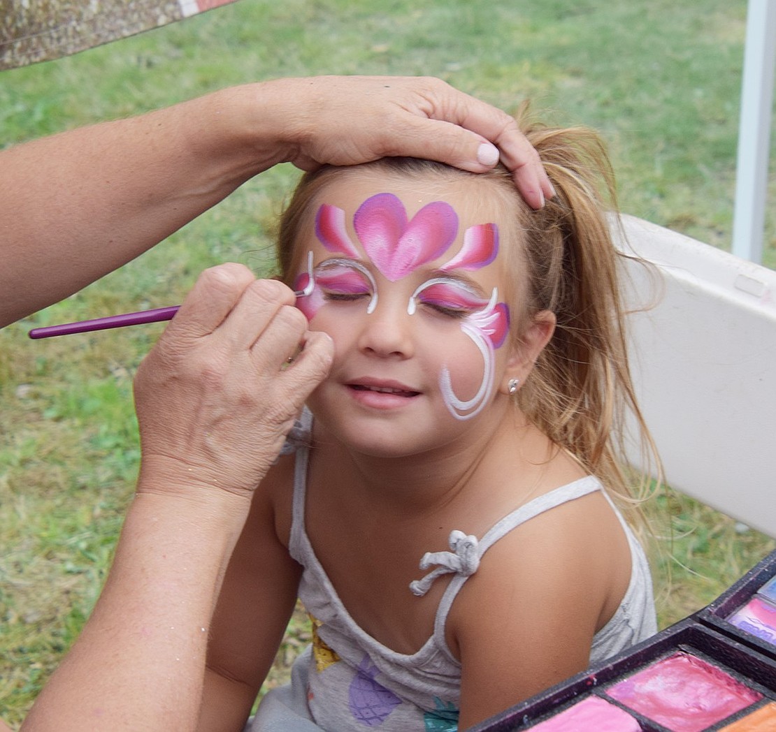 Calm and patient, 4-year-old Westchester Avenue resident Eva Tedesco sits still while an elegant design gets painted on her face at Port Chester Day on Saturday, Aug. 24.