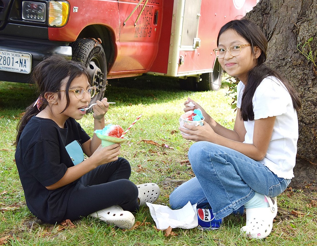 Olivia Street neighbors Emmi Renoj, 7, and Amy Vicente, 10, chill out in the shade of a tree while enjoying some frozen treats.