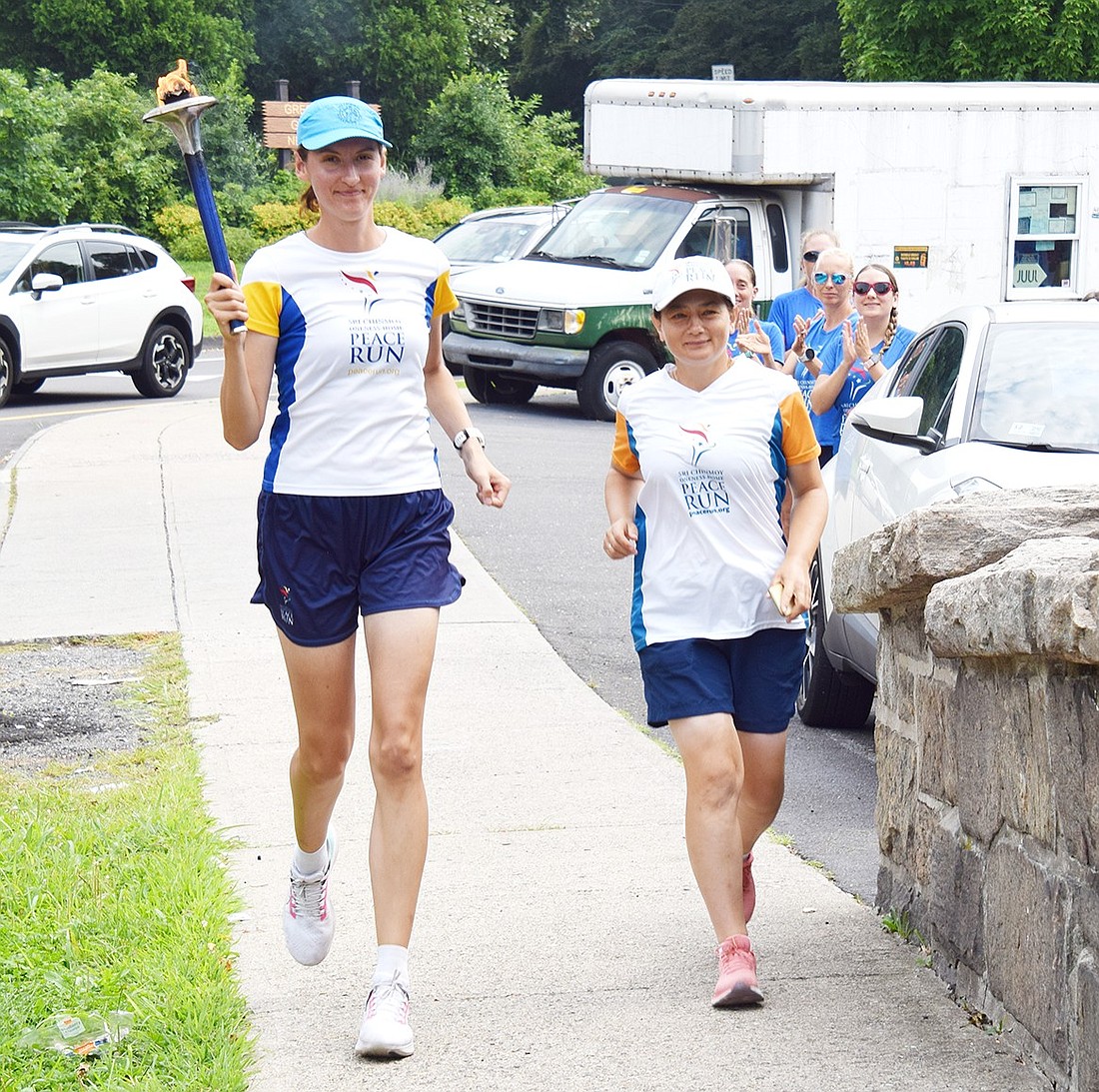 Todorka Petrovska (left), a citizen of North Macedonia, and Ruslana Kupinets, from Ukraine, run across the Hillside Avenue bridge on Aug. 17 as they start their trek carrying a torch for peace through Port Chester. They, along with others, spent four months taking the flame across the U.S. as part of the Sri Chinmoy Oneness-Home Peace Run.