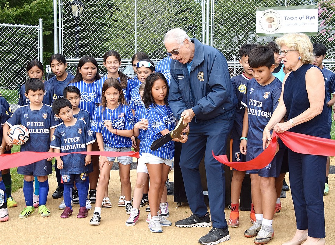 With help from 9-year-old Port Chester resident Mia Carranza, Rye Town Supervisor Gary Zuckerman cuts the ceremonial ribbon to open the newly renovated sports fields at Crawford Park on Friday, Aug. 30. They are surrounded by young local athletes ready to immediately enjoy the greenspace.