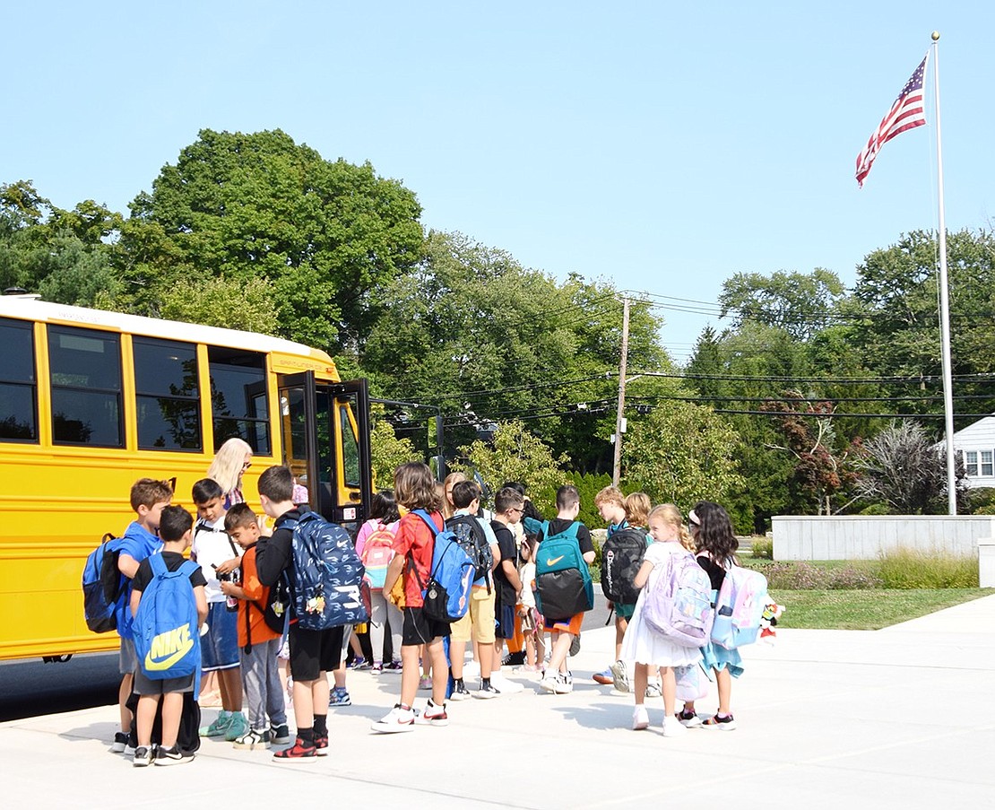 A group of Ridge Street School elementary students make their way onto a school bus to head home after class.